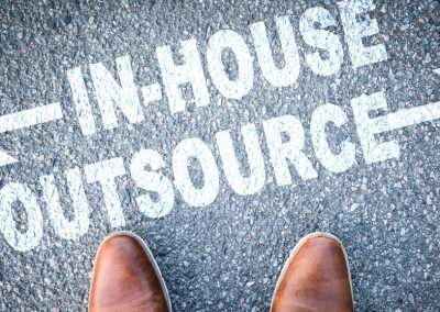 words in-house vs outsourcing written on pavement