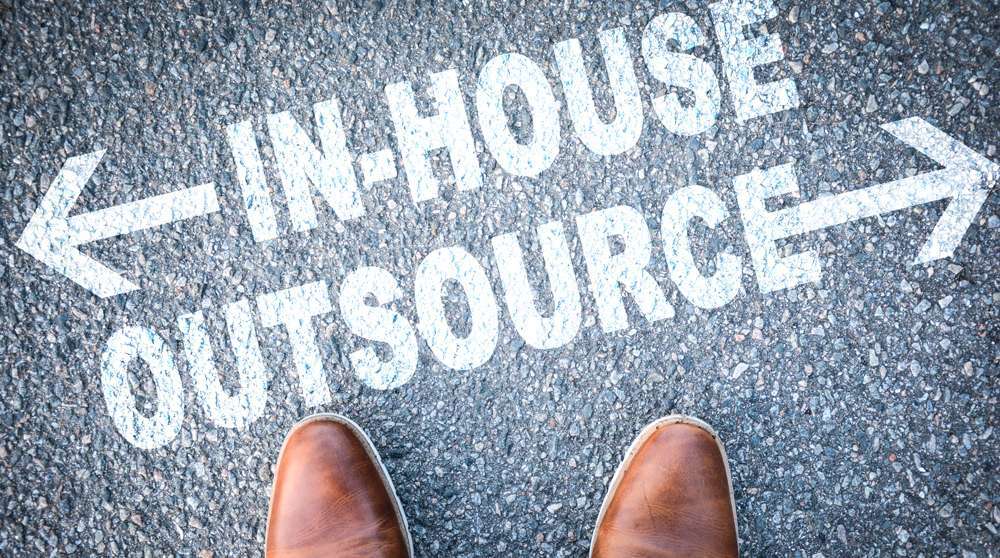 words in-house vs outsourcing written on pavement