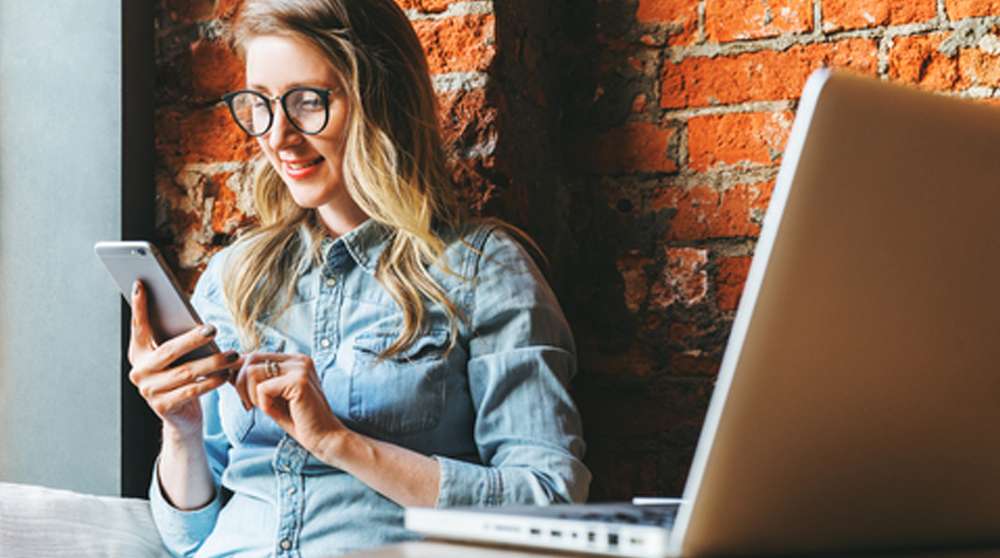 working sitting in front of brick wall using phone