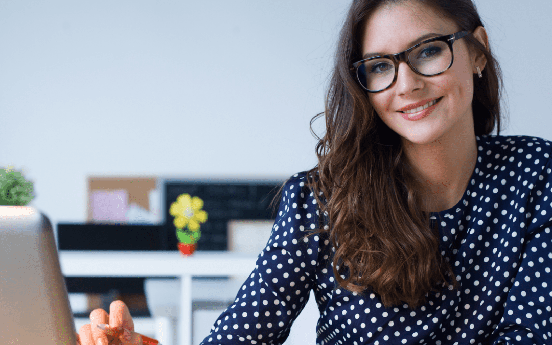 woman in polka dot top smiling in front of computer