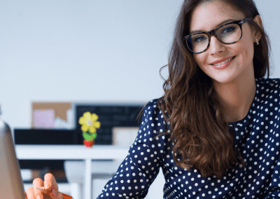 woman in polka dot top smiling in front of computer