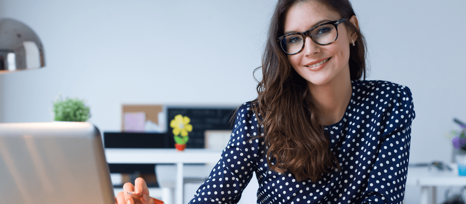 woman in polka dot top smiling in front of computer