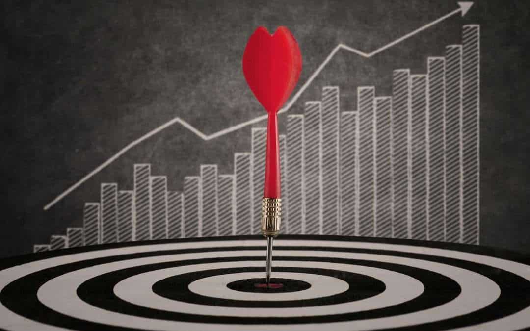 dartboard with arrow in bullseye, upward trending graph in background