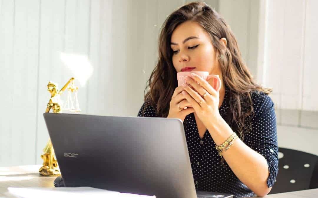 woman drinking coffee in front of computer