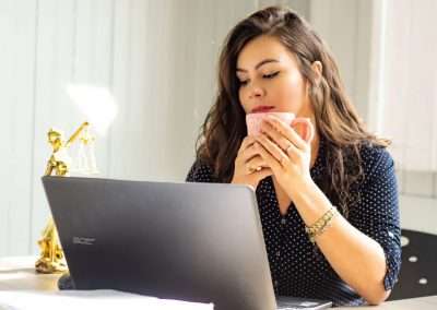 woman drinking coffee in front of computer