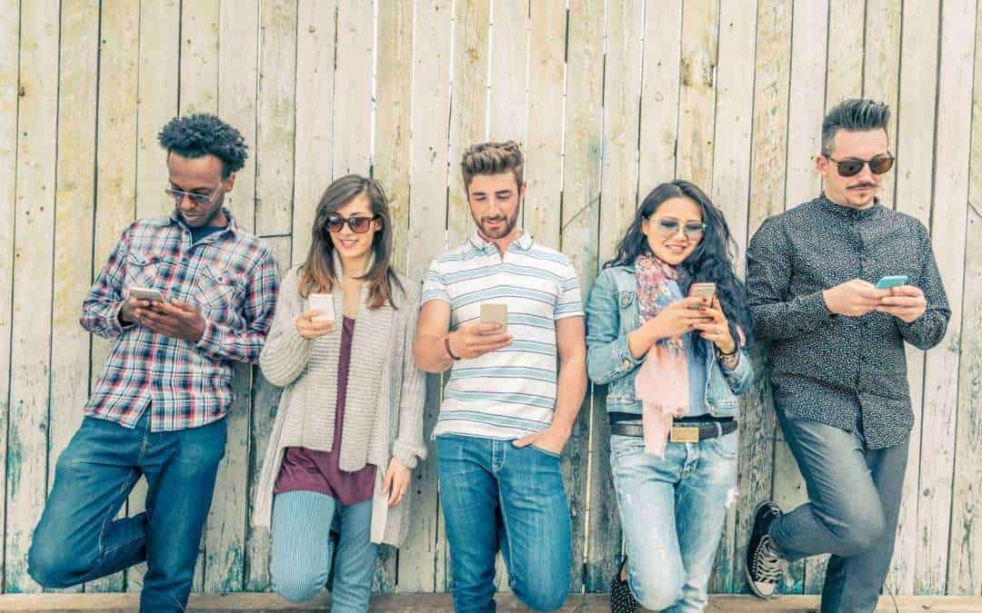 people standing against fence and texting