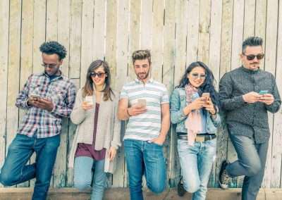 people standing against fence and texting