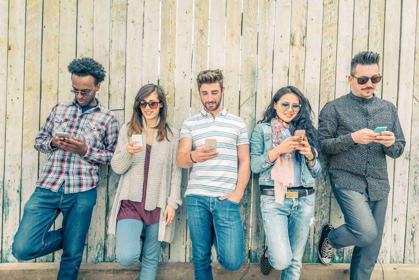 people standing against fence and texting