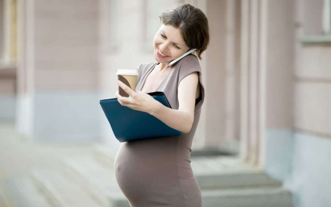 preganant woman on the phone and holding laptop