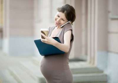 preganant woman on the phone and holding laptop