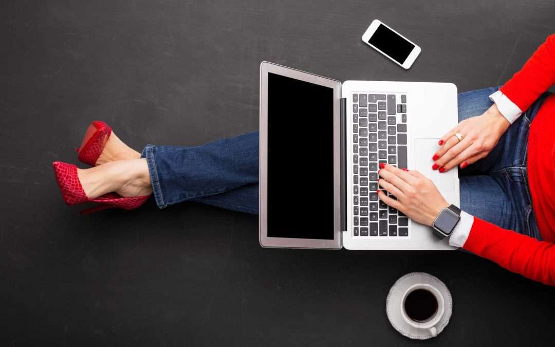 woman in red heels and read sweater working on a laptop