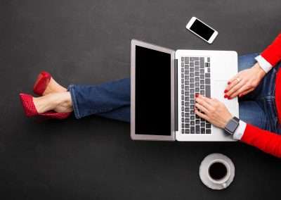 woman in red heels and read sweater working on a laptop