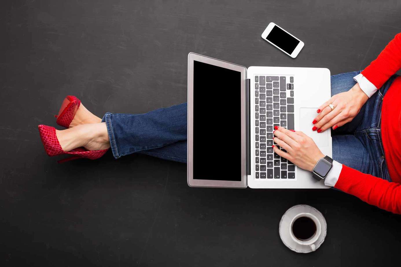 woman in red heels and read sweater working on a laptop