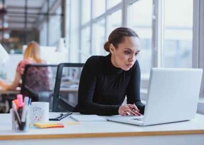 serious woman staring at laptop in open concept office