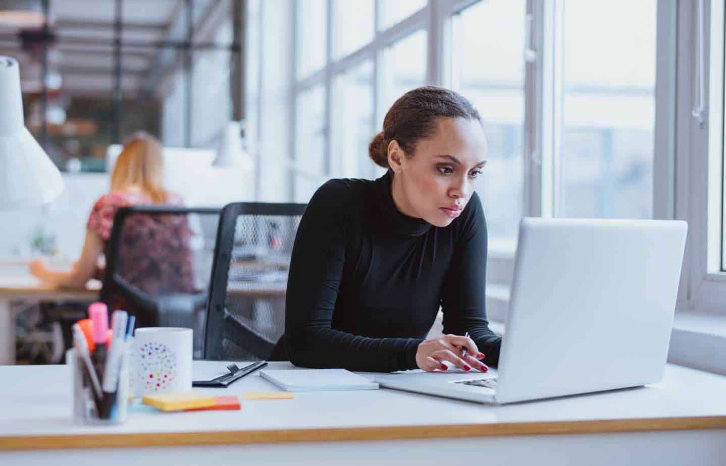 serious woman staring at laptop in open concept office