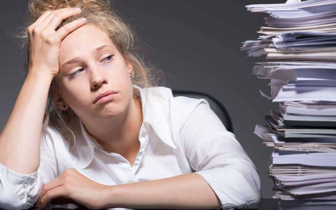 Tired woman next to large stack of papers