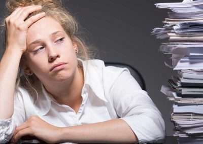 Tired woman next to large stack of papers