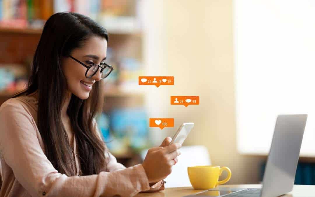 Happy latin female blogger using smartphone with social media notification icons, sitting in cafe, free space