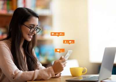 Happy latin female blogger using smartphone with social media notification icons, sitting in cafe, free space