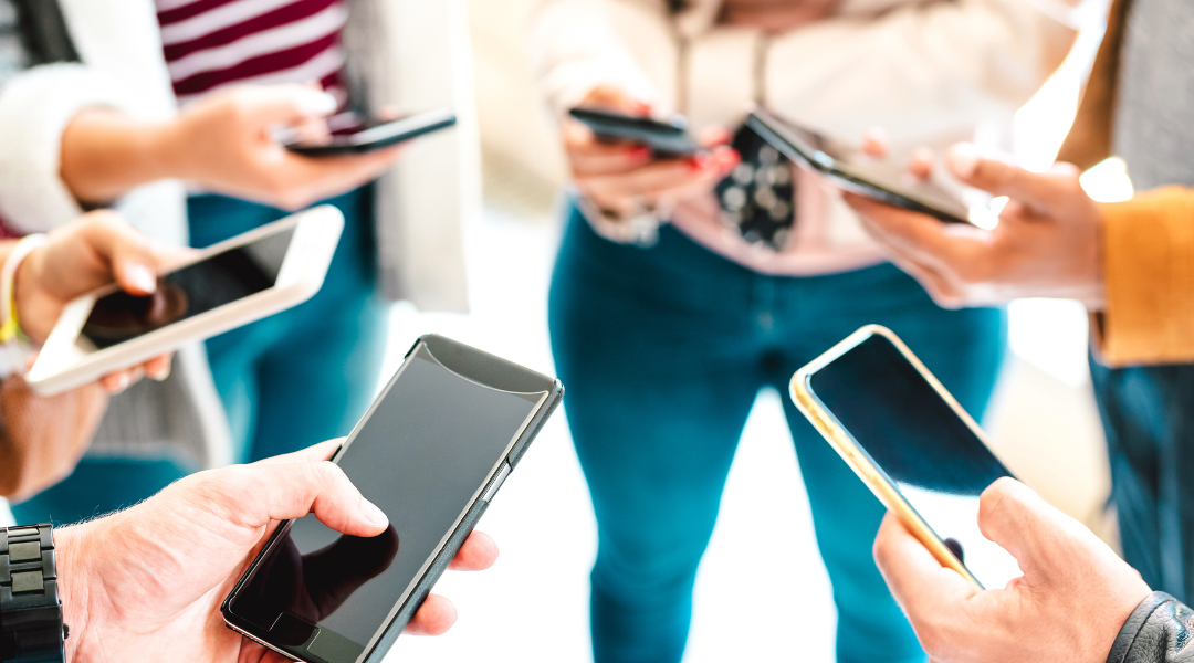 A group of people looking down at their cell phones.