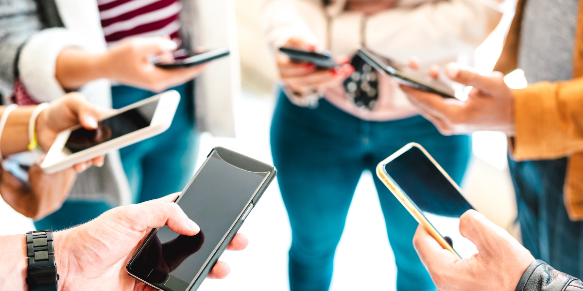 A group of people looking down at their cell phones.