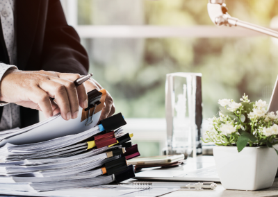 Close-up of a man sifting through a large stack of papers, binder-clipped into different stacks.