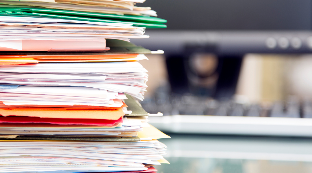 Closeup of a large stack of manila files and folders.