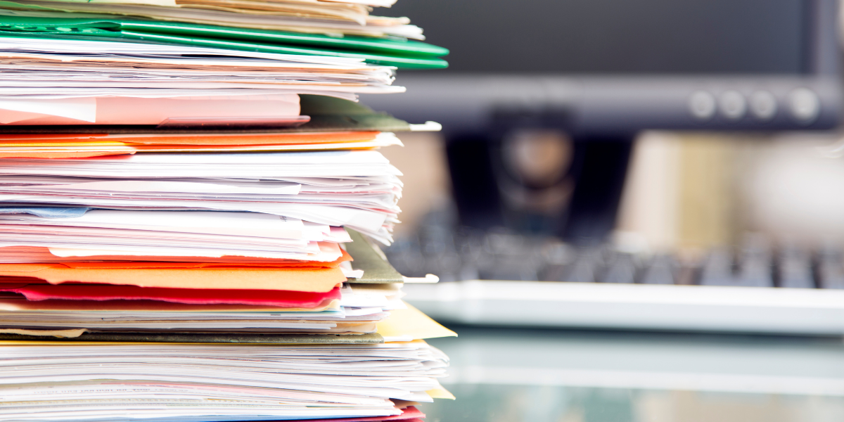 Closeup of a large stack of manila files and folders.