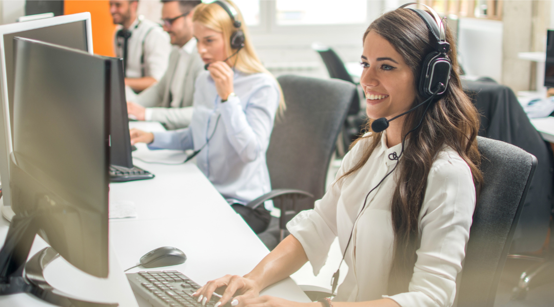 Two men and two women wearing headsets, working in a call center office.