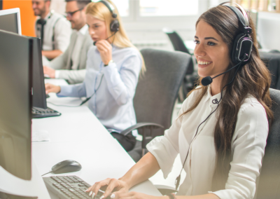 Two men and two women wearing headsets, working in a call center office.