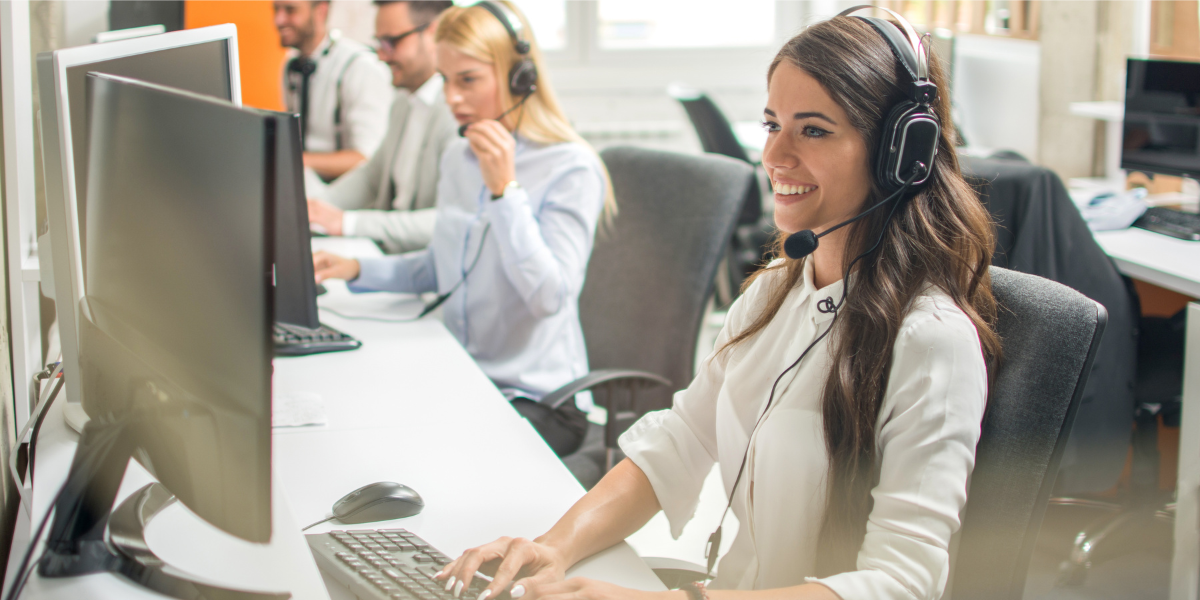 Two men and two women wearing headsets, working in a call center office.