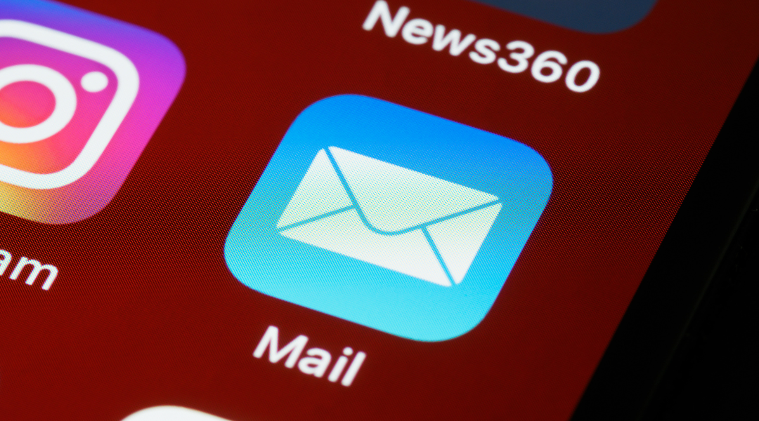 Extreme close-up of a red cellphone screen with social media icons, focusing on the mail icon.