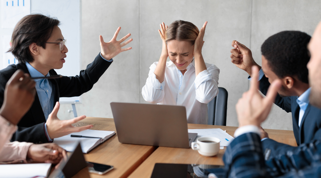 People in a meeting are gesturing and looking tense.