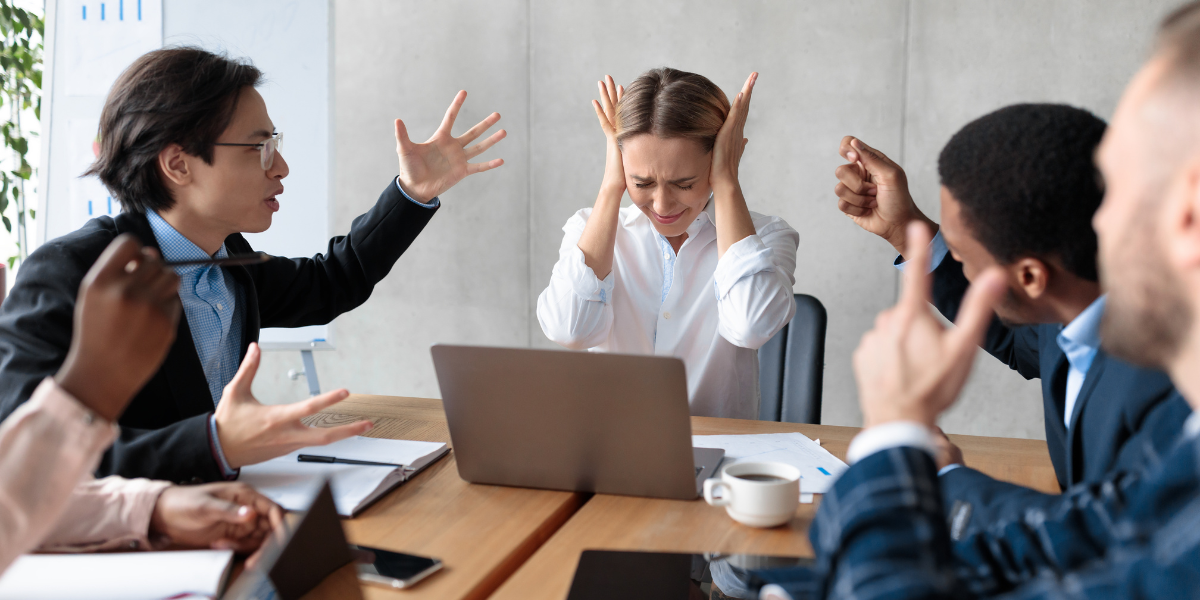 People in a meeting are gesturing and looking tense.