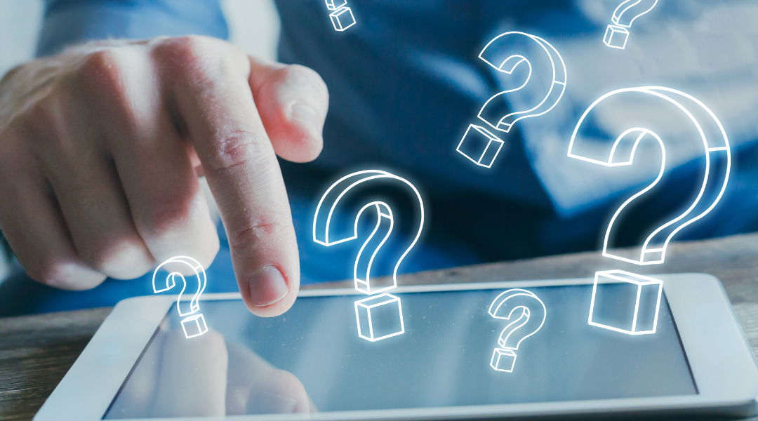 a mans hand tapping a tablet screen. There are question mark icons hovering over the tablet.