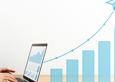 Hands typing on a laptop with graphs on the screen, including an upward bar graph and a flying paper airplane icon, indicating increasing sales.