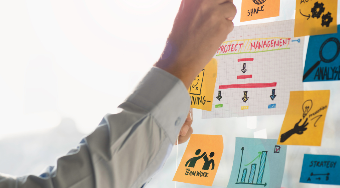 hands placing bright-colored sticky notes on a project management board.