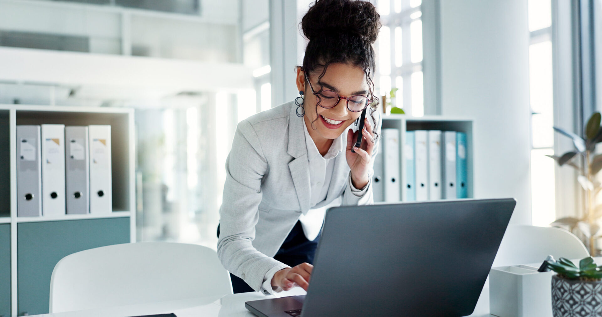 Happy corporate woman working in law office on cellphone.