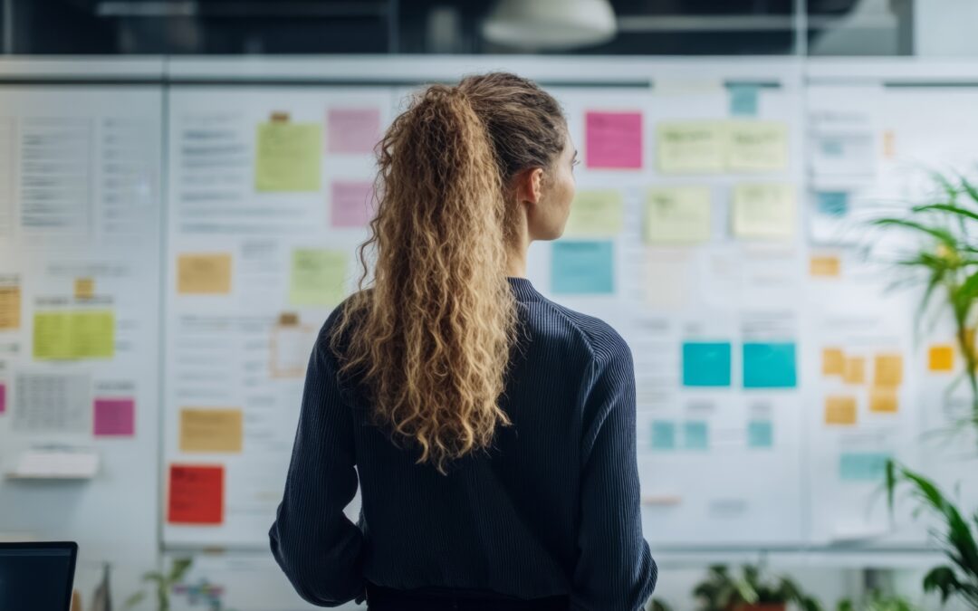 Back view of woman standing in front large marketing task boards