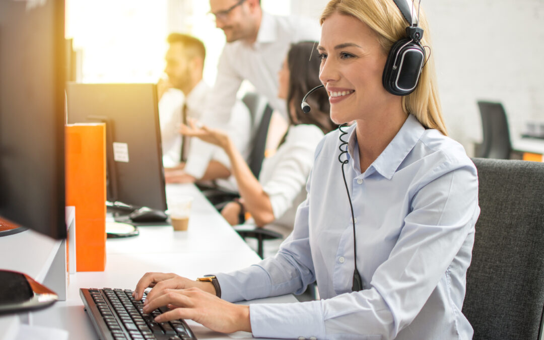 Outsourced customer service professional in headset working on computer in call center 