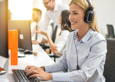 Outsourced customer service professional in headset working on computer in call center