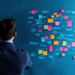 Business leader overwhelmed by tasks, looking at post-it notes of admin duties to delegate.
