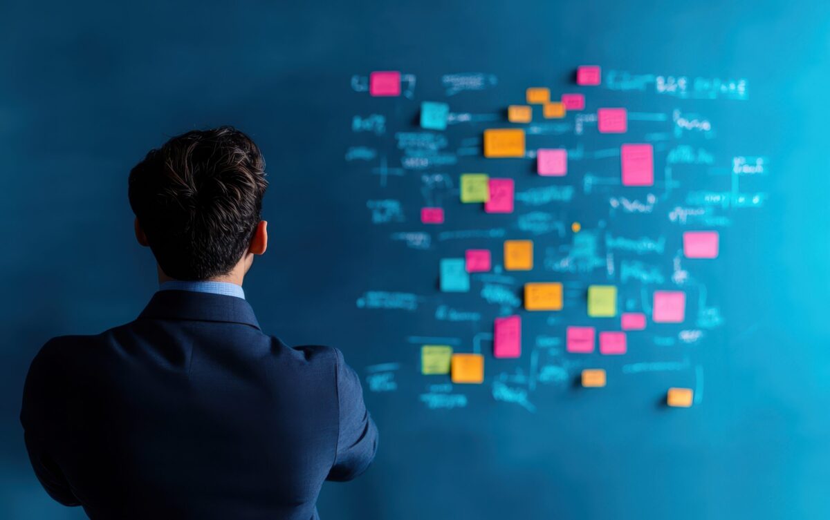 Business leader overwhelmed by tasks, looking at post-it notes of admin duties to delegate.