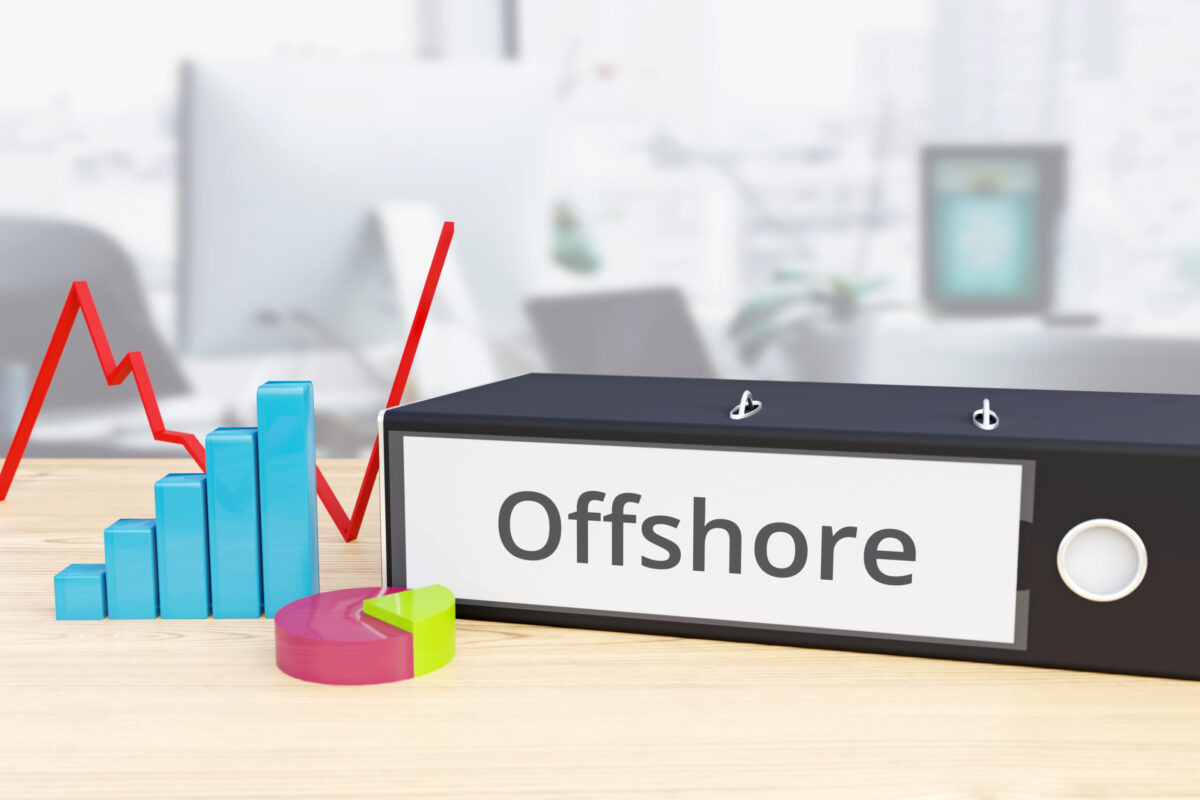 Folder on desk with offshore label beside finance diagrams.