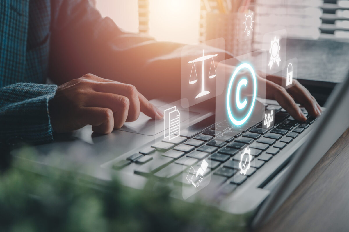 Corporate Attorney using laptop computer on desk with copyright icon background.