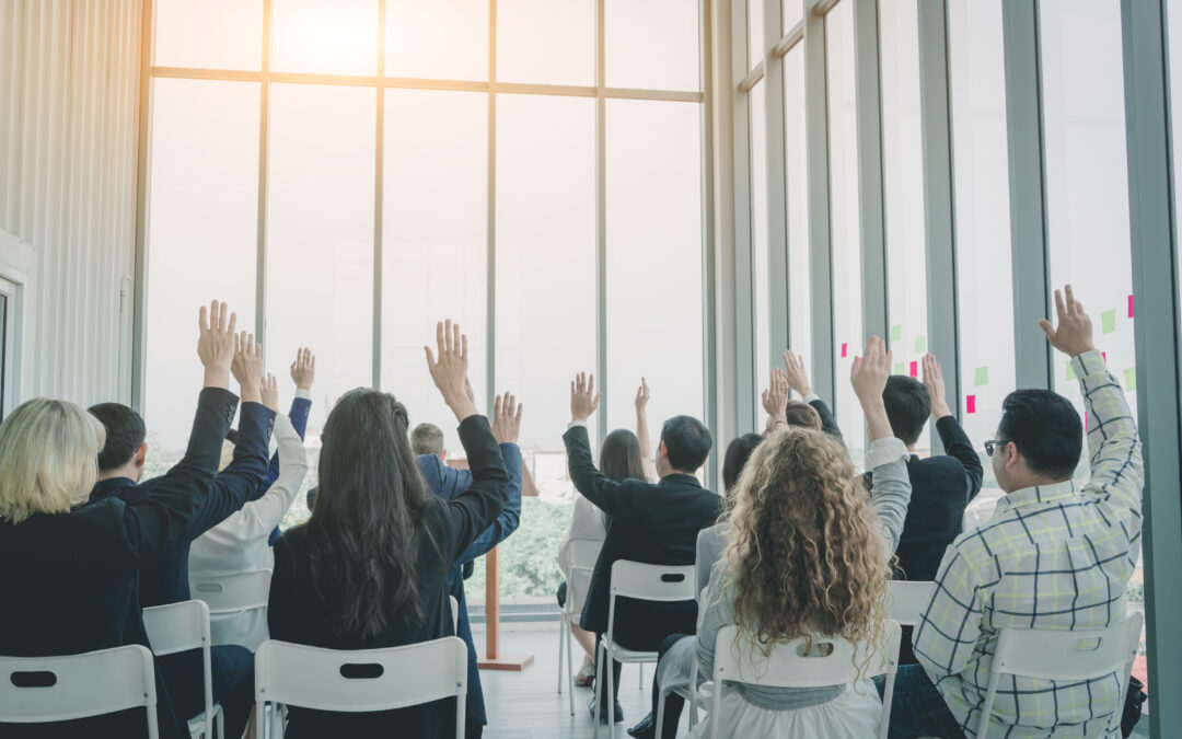 Group of business people raise hands up to agree,people raising hands during seminar,Audience voting in professional education surrounding.
