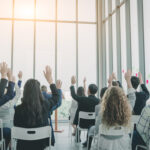 Group of business people raise hands up to agree,people raising hands during seminar,Audience voting in professional education surrounding.