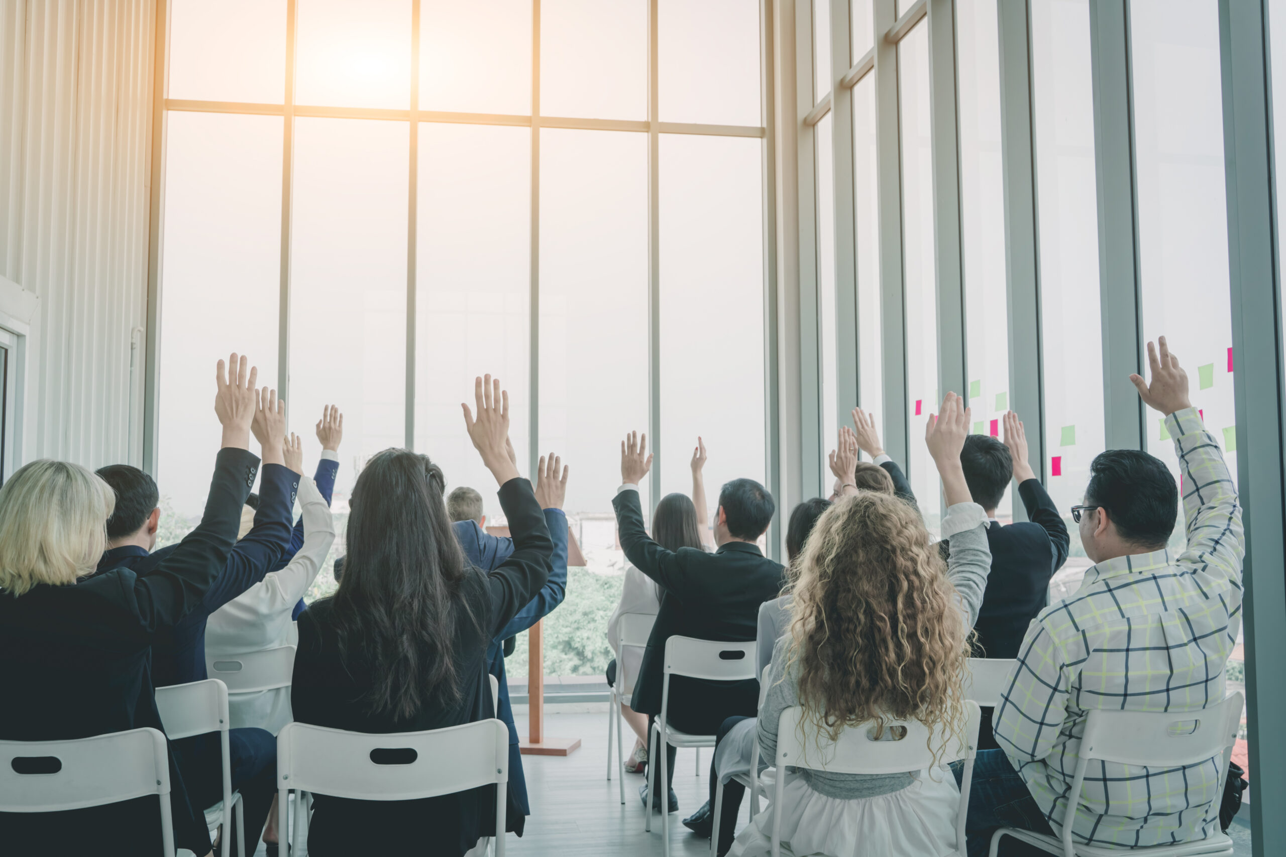 Group of business people raise hands up to agree,people raising hands during seminar,Audience voting in professional education surrounding.