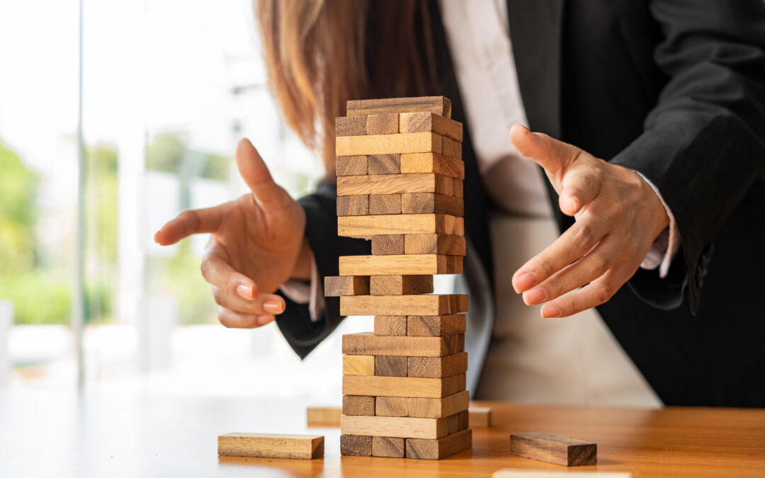 businesswoman holds her hand on a wooden block with a weak base. It is like a business risk mitigation strategy. and project management the best of the business