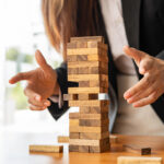 businesswoman holds her hand on a wooden block with a weak base. It is like a business risk mitigation strategy. and project management the best of the business